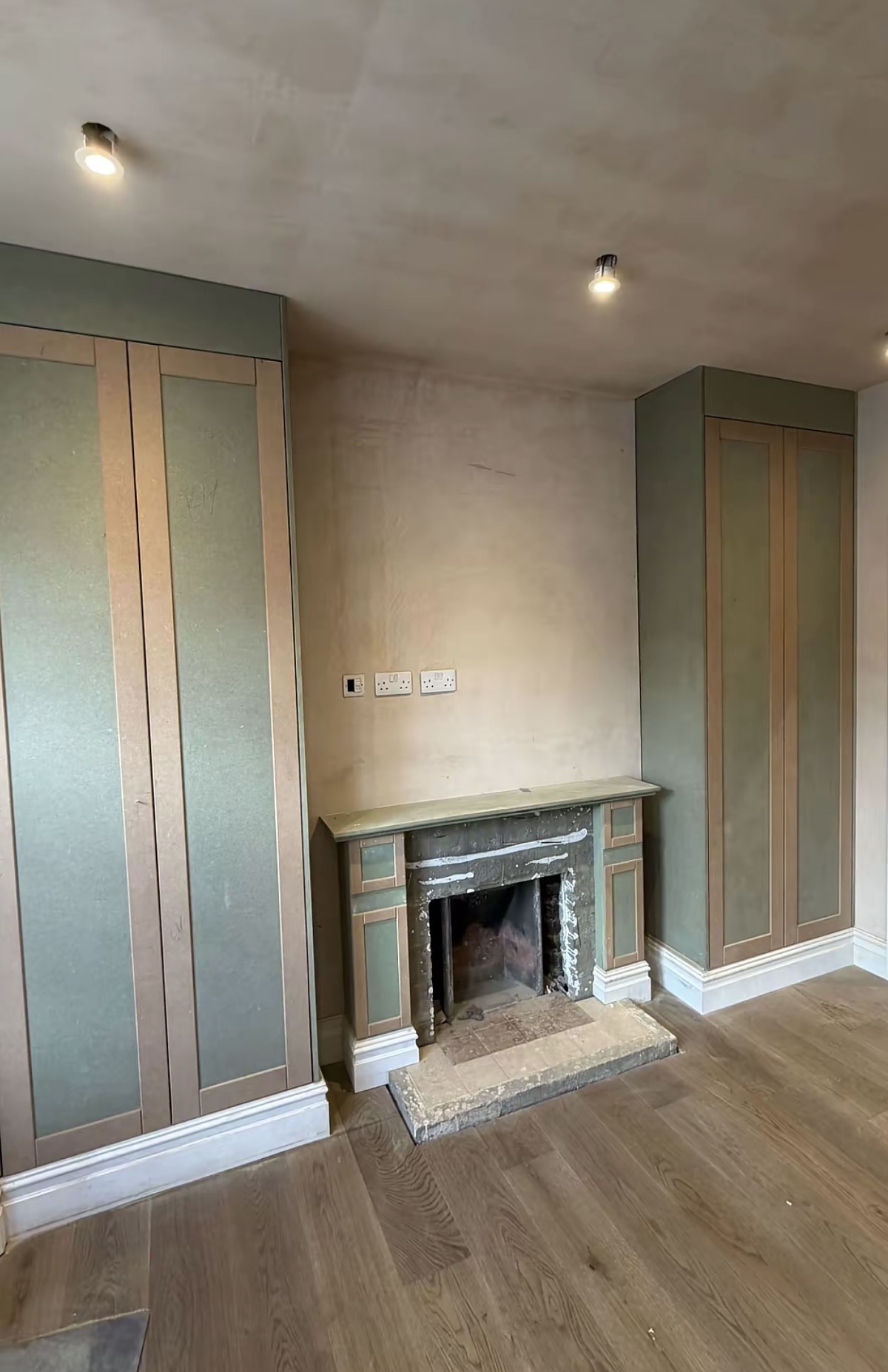 Fitted cabinetry and panelling around a fireplace during installation